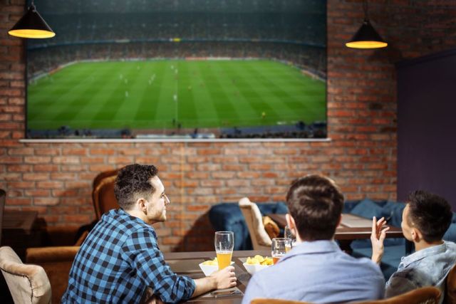 Menschen die in gemütlicher Runde in einer Sportbar sitzen und Bier trinken.